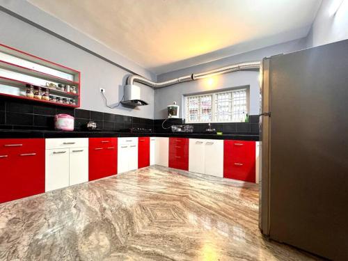 a kitchen with red and white cabinets and a refrigerator at Ariana Homestay in Siliguri