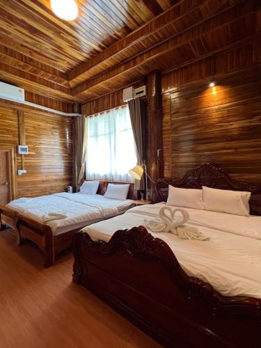 two beds in a room with wooden walls at ห้างหุ้นส่วนจำกัด บ้านเถ้าแก่ in Ban Muang Baeng