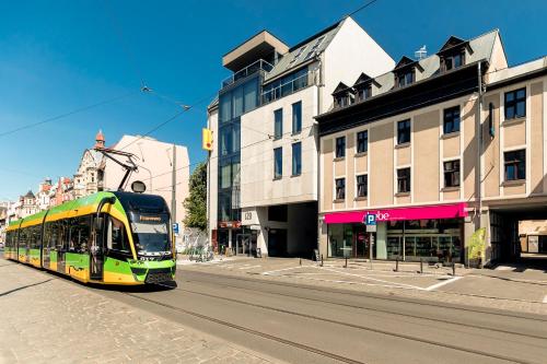 a yellow and green bus driving down a city street at Cooltour Hostel in Poznań