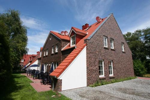 a large brick building with a white garage at Ferienhäuser Greetsiel - Urlaub mit Haustier in Ostfriesland in Greetsiel