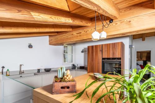 a kitchen with wooden ceilings and a wooden table at BOTTONERA casa vacanza in Chiavenna