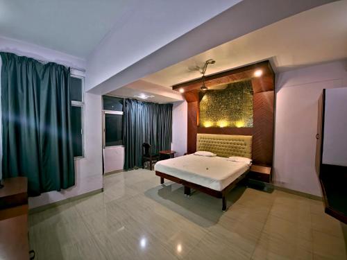 a bedroom with a bed and a green curtain at Hotel Blue Residency in Nāgercoil