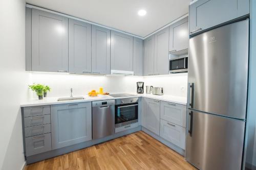 a kitchen with white cabinets and a stainless steel refrigerator at Forenom Serviced Apartments Helsinki Töölö in Helsinki