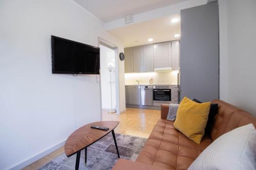 a living room with a brown leather couch and a television at Forenom Serviced Apartments Helsinki Töölö in Helsinki