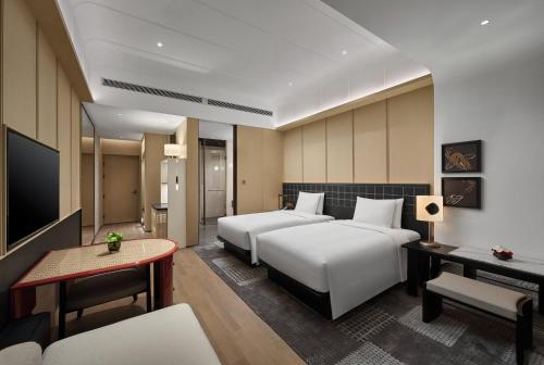 a hotel room with two beds and a television at HUALUXE Shenzhen Bao'an in Shenzhen
