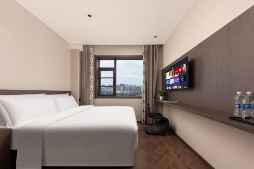 a hotel room with a white bed and a tv at 木桃酒店Mutao Hotel in Hangzhou