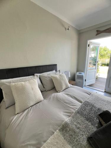 a bed with white sheets and pillows in a bedroom at Charming Flatlet Near the Amazing Sunset Beach in Cape Town