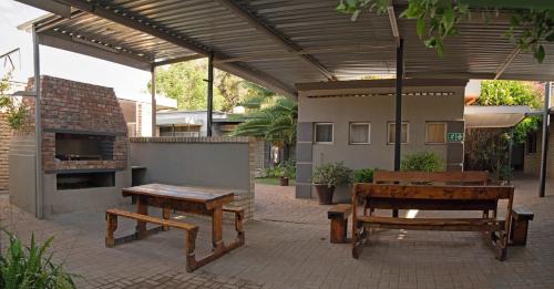 a patio with two benches and a fireplace at Gold Guest & Conference in Welkom