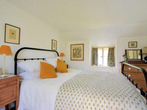 a bedroom with a large white bed with orange pillows at Church Cottage in Bridport