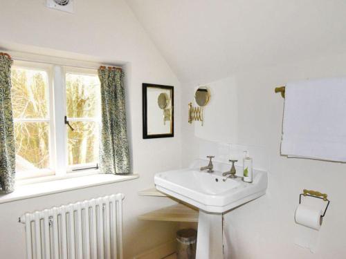 a white bathroom with a sink and a window at Church Cottage in Bridport