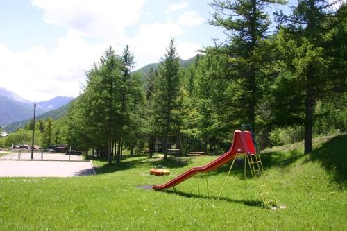 a playground with a red slide in the grass at Gîtes Simond in Arvieux