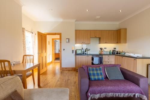 a living room with a purple couch and a kitchen at Kennacoil in Dunkeld