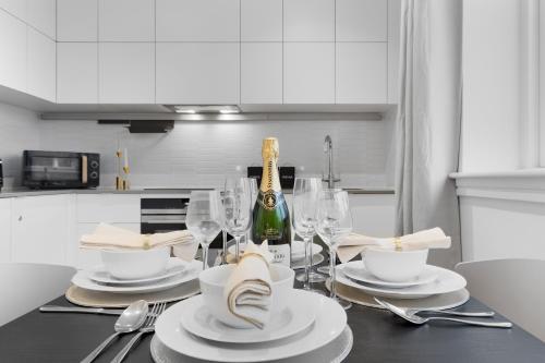 a dining table with a bottle of champagne and glasses at Stylish Retreats on Olympic Way in London