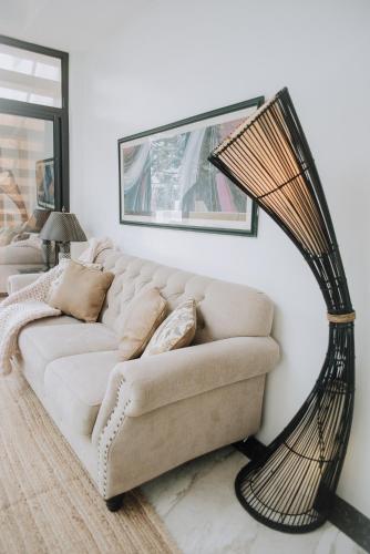 a living room with a white couch with a rattan lamp at The French Villa-Santander Cebu in Santander