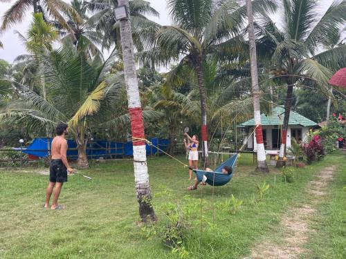 a man in a hammock tied to a palm tree at Lake Homes in Varkala