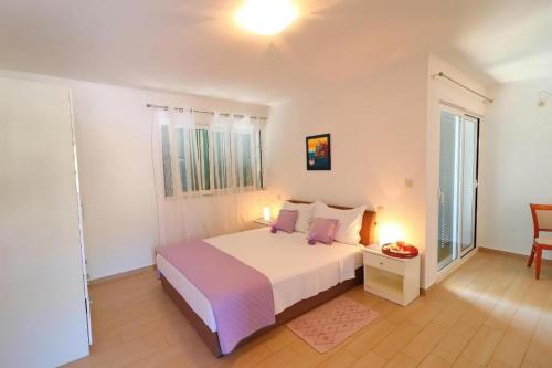 コルチュラにあるCozy Sea View House with Poolのベッドとテーブルと椅子のある白い寝室