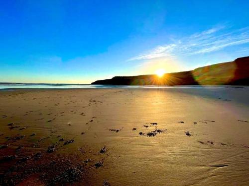 einen Strand mit Fußabdrücken im Sand bei Sonnenuntergang in der Unterkunft Moor Crest in Scarborough
