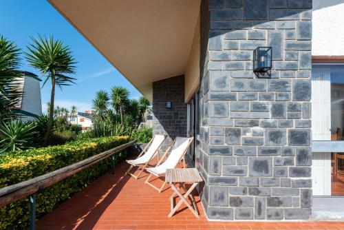 a group of chairs sitting next to a stone wall at Atlantic Villa - Mindelo Beach in Vila Chã