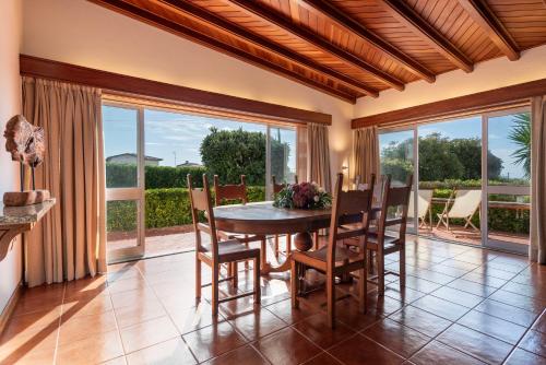 a dining room with a table and chairs and windows at Atlantic Villa - Mindelo Beach in Vila Chã