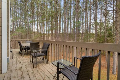 a wooden deck with chairs and a table on it at Le Champetre Tremblant 2bdrs Condo W Fireplace in Mont-Tremblant
