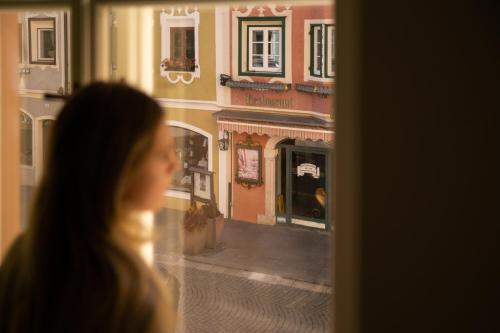 a woman looking out of a window at a building at Casa Fellin Guesthouse in Vipiteno