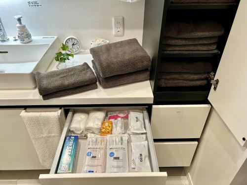 a white bathroom with a sink and towels at Accessible Four-Bedroom House near Kuzuha Station! in Hirakata