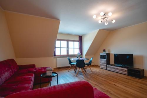 a living room with a red couch and a table at Fichtelberghaus in Kurort Oberwiesenthal