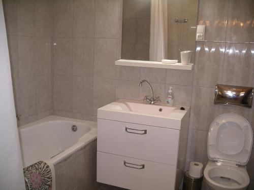a bathroom with a sink and a toilet and a tub at Centrum Suite in Hévíz