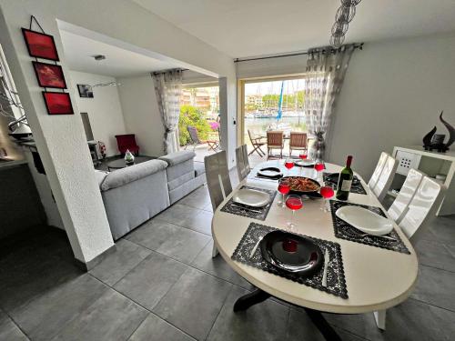 un salon avec une table à manger et un canapé dans l'établissement Marina lumineuse avec terrasses, clim, parking & accès plage privée - FR-1-387-181, au Cap d'Agde