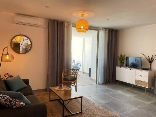 a living room with a couch and a tv at Appt Oceanne vue sur l'océan centre ville St Leu 5 min lagon in Saint-Leu