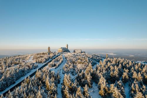 a winter view of a mountain with snow covered trees at Fichtelberghaus in Kurort Oberwiesenthal