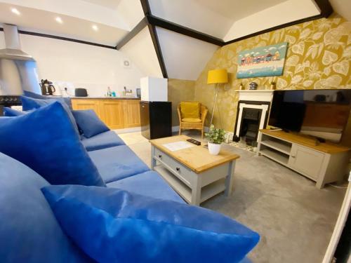a living room with a blue couch and a tv at The Beach Hut Walk to Beach Sleeps 4 Parking Pet Friendly in Bournemouth