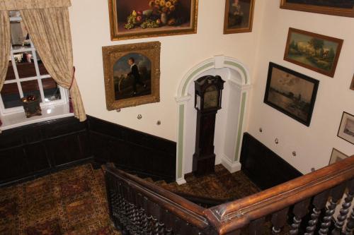 a stairway with a clock and paintings on the wall at Mangreen Country House in Norwich