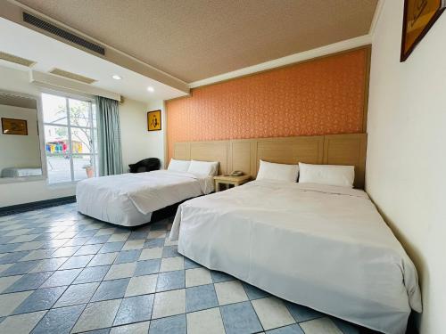 a hotel room with two beds and a window at 巨地花園莊園 in Xinshi