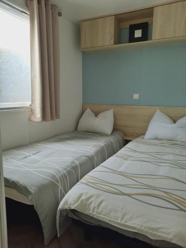 deux lits dans une petite pièce avec une fenêtre dans l'établissement Mobil home charmant EMPL 521, aux Mathes