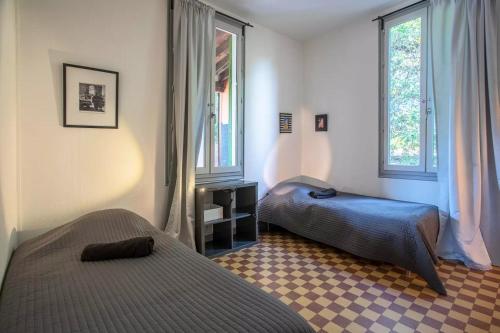 Dos camas en una habitación con dos ventanas. en Villa les Grillons, en Hyères