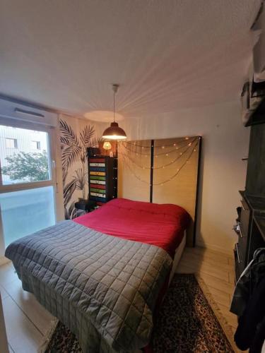 une chambre avec un lit avec une couverture rouge dans l'établissement Appartement bord de Garonne avec Parking, à Toulouse
