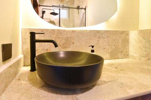 a large black sink in a bathroom with a mirror at Castle Black, Infinite Ocean Sunsets at the Skyloft in Fumba Town in Dambani