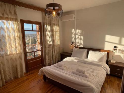 una camera da letto con un letto con lenzuola bianche e una finestra di Villa Hill a Tríkala