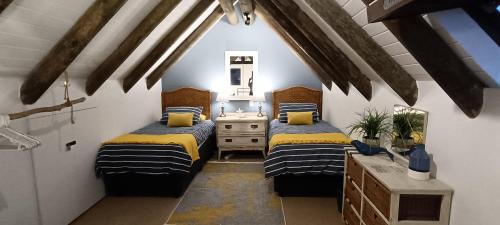 a bedroom with two beds and a dresser and a mirror at River View Cottage - at the Breede in Witsand