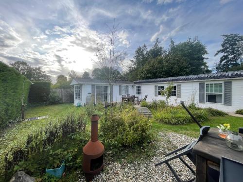 a bottle of wine in the yard of a house at Your Private Zeeland Getaway - Cosy Home With Large Garden in Heinkensand