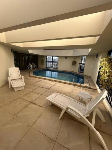 a swimming pool with two chairs and avisor at Hotel Biena Sena Madureira PqIbirapuera Com Garagem 907 in Sao Paulo