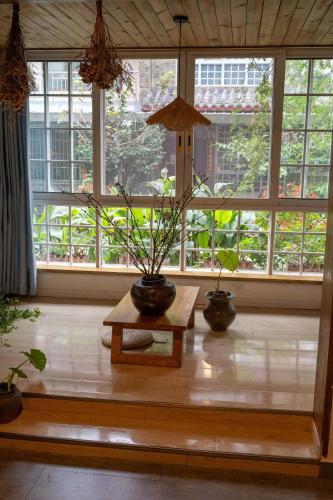 a room with two potted plants on a table in front of windows at Qingcheng Mountain Huakai Shiminsu in Dujiangyan
