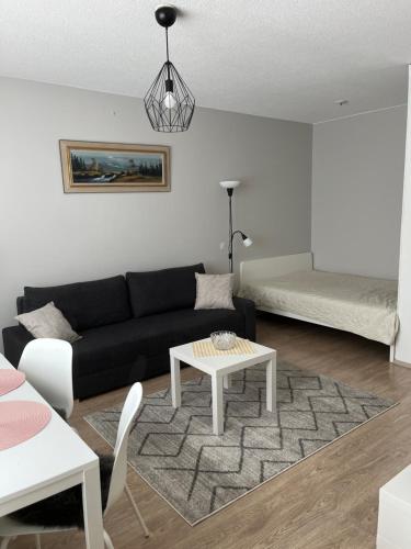 a living room with a black couch and a table at Rovaniemi Studio 32 in Muurola
