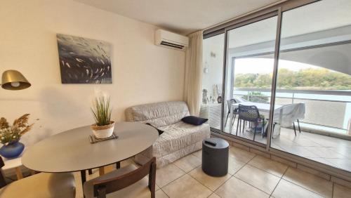 un salon avec une table et un canapé dans l'établissement Quai de la lagune - vue sur la Marina, à Saint-Cyprien