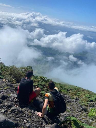 two people sitting on top of a mountain looking at the clouds at Hostal Xilotl in San José del Sur