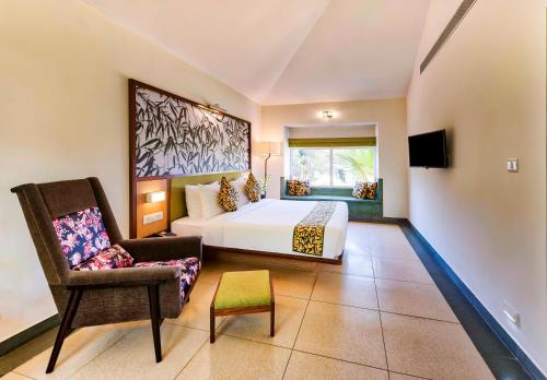 a bedroom with a bed and a chair and a tv at Sterling Wayanad in Sultan Bathery