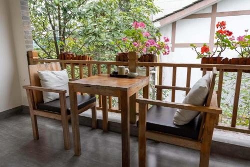a wooden table and chairs on a balcony with flowers at Qingcheng Mountain Huakai Shiminsu in Dujiangyan