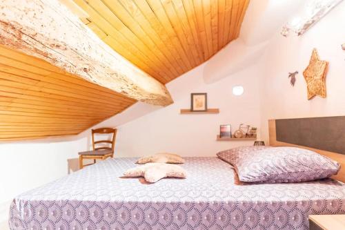 une chambre avec un grand lit avec un plafond en bois dans l'établissement Maison de village l'étoile d'Auré Moustiers, à Moustiers-Sainte-Marie