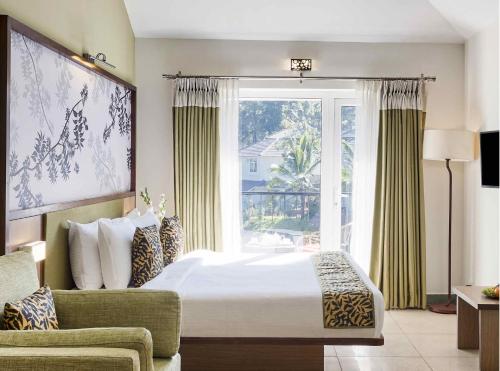a bedroom with a bed and a large window at Sterling Wayanad in Sultan Bathery